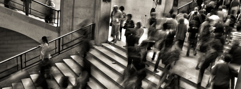 People rushing up and down a staircase in an atrium