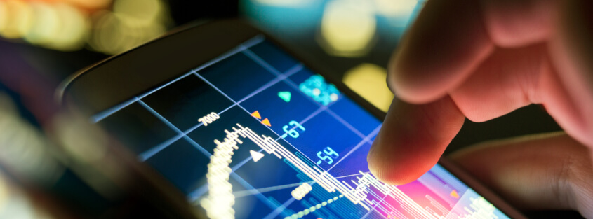 Mobile phone with a stock exchange app displayed and a finger perusing the trend line